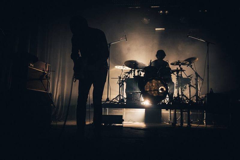 a man is standing in front of a drum set on a stage .