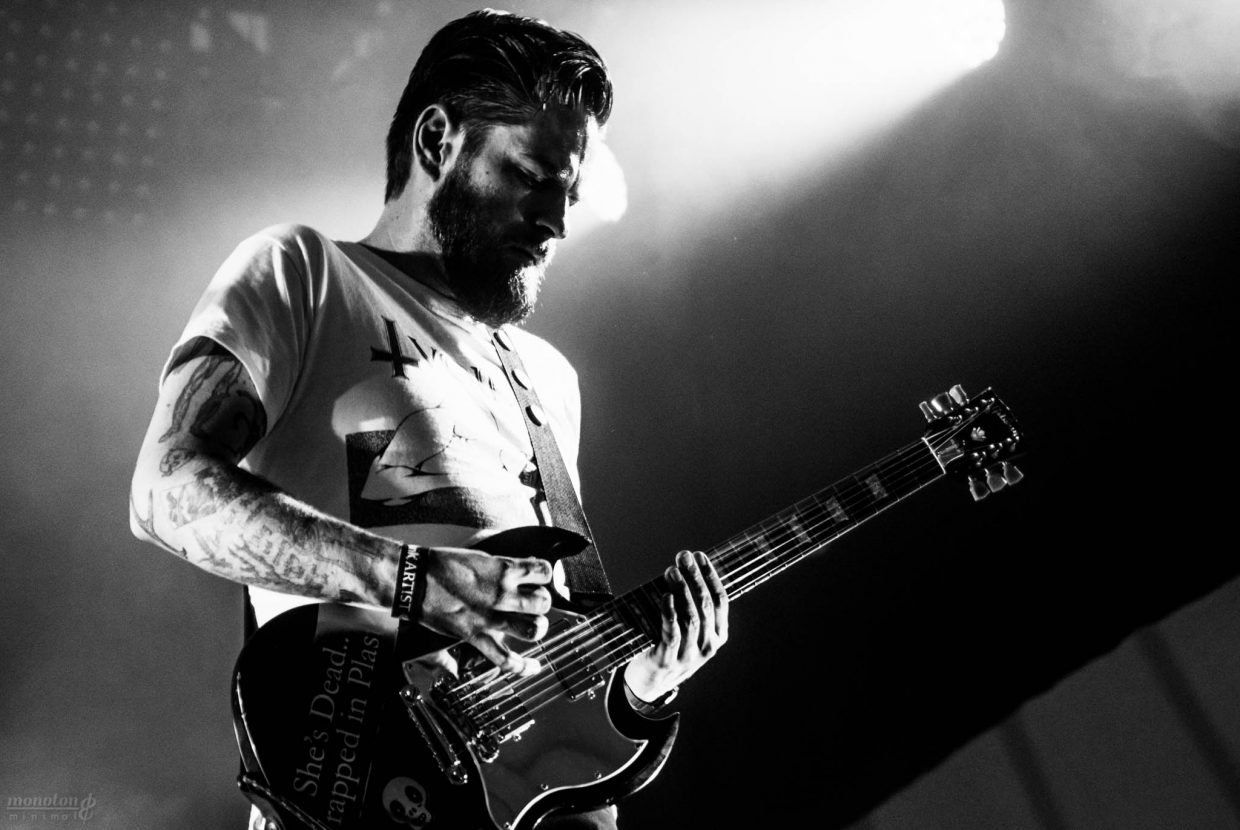 a man with a beard is playing a guitar on a stage in a black and white photo .