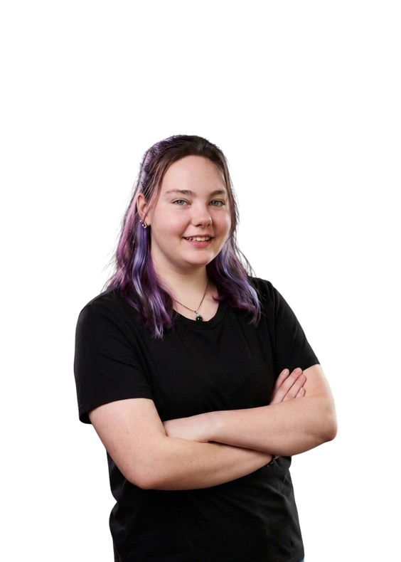 Person with purple hair wearing a black shirt, smiling with arms crossed on a white background