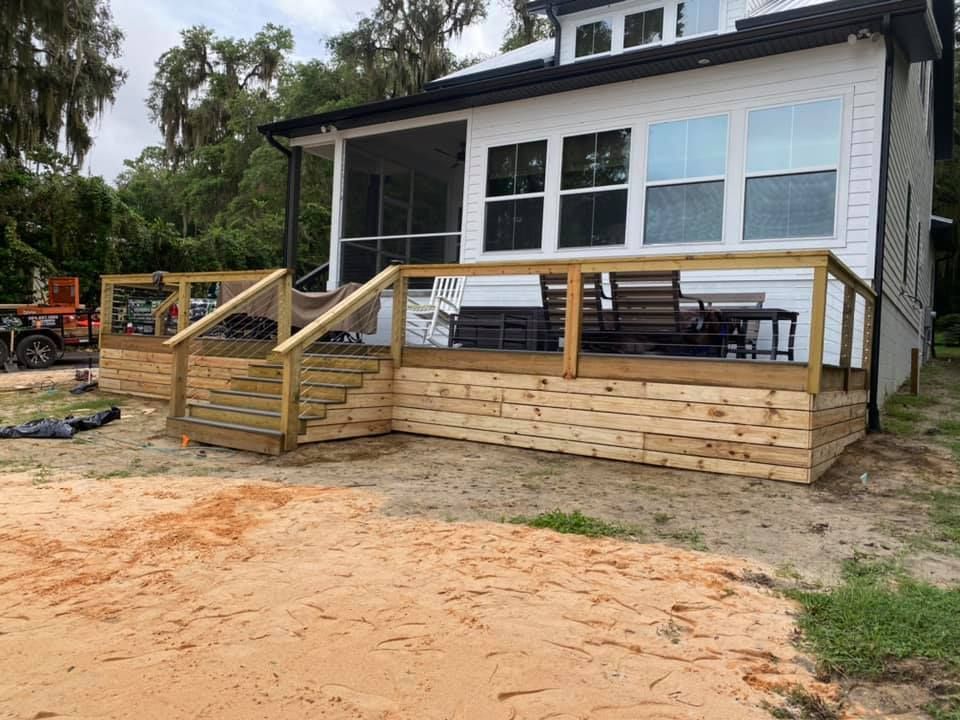 A woodworker in a shop uses a pencil and metal ruler to measure and mark a piece of wood on a workbench.