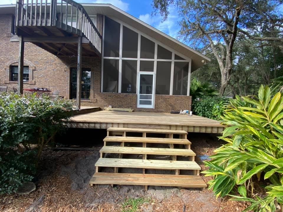A worker uses a screwdriver to adjust a white window frame, with a caulk gun resting on the sill nearby.