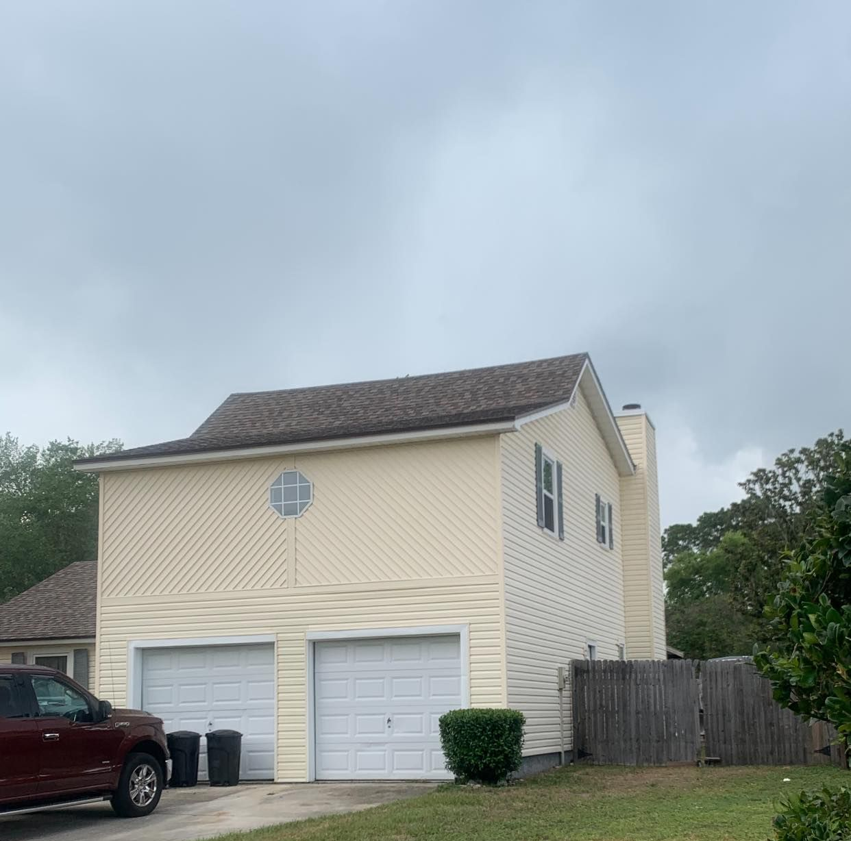 A person in white work clothes and black gloves pours white paint from a can into a blue paint tray.