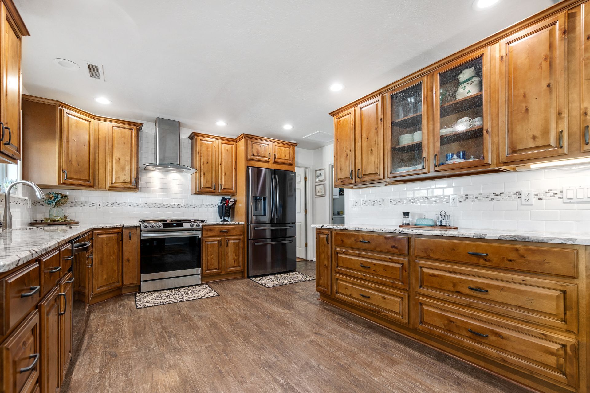 A person in dark blue overalls uses a yellow power drill to attach a white furniture leg to a wooden table.