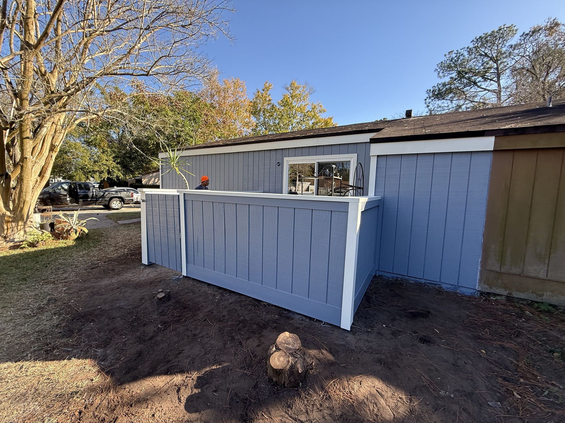 A gloved hand uses a paint roller to apply grey paint to a wall.