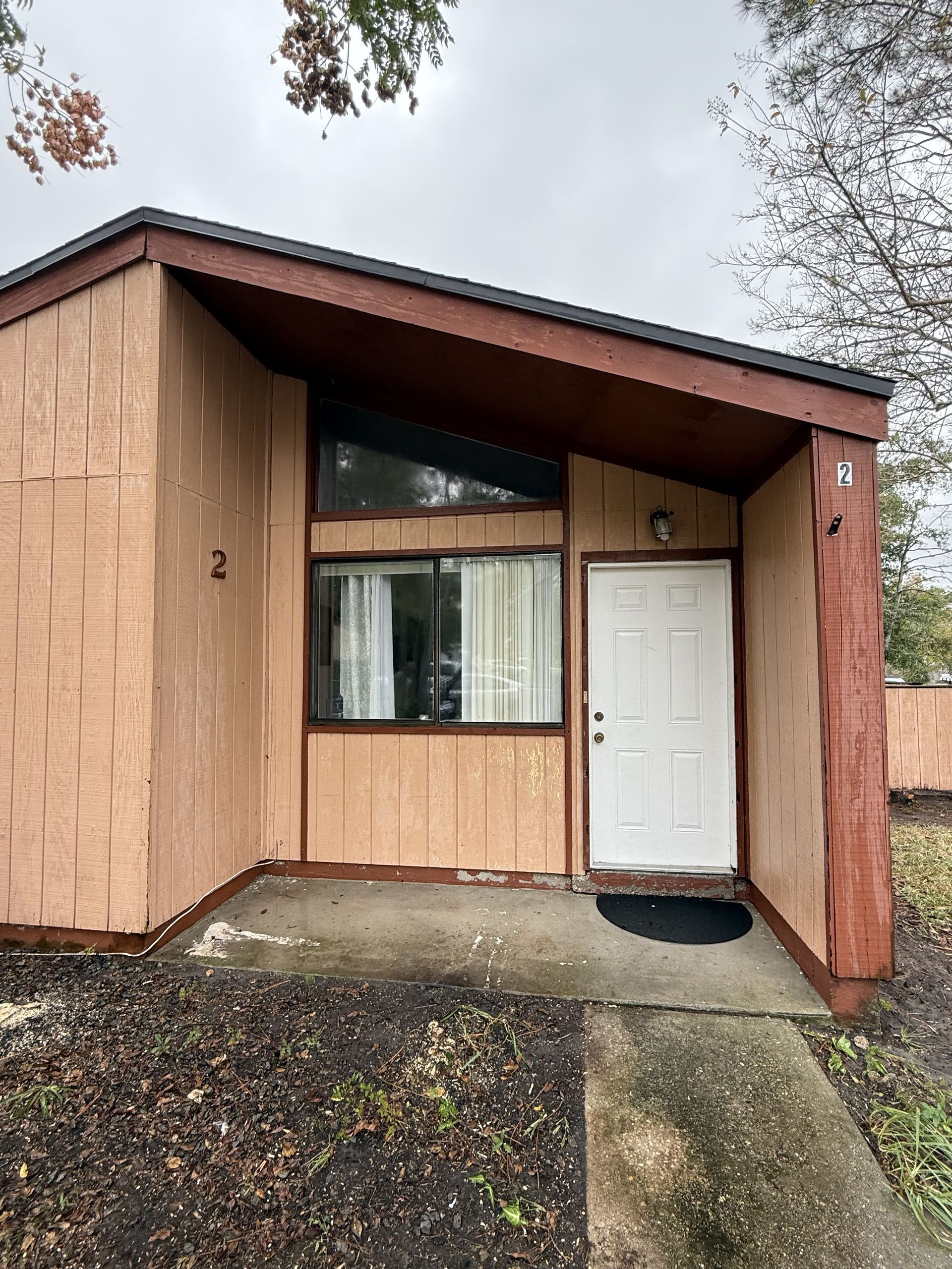 Two workers in yellow shirts suspended on platforms paint the blue exterior wall of a building white.