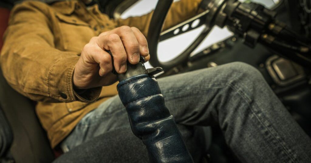 A man is sitting in a car holding a steering wheel. | Country Tire