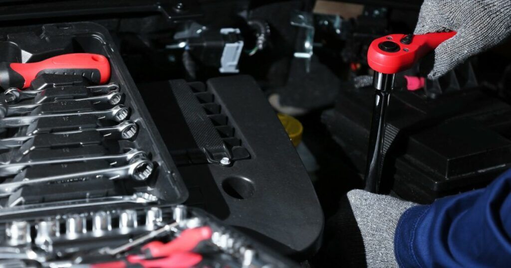 A person is working on the engine of a car. | Country Tire