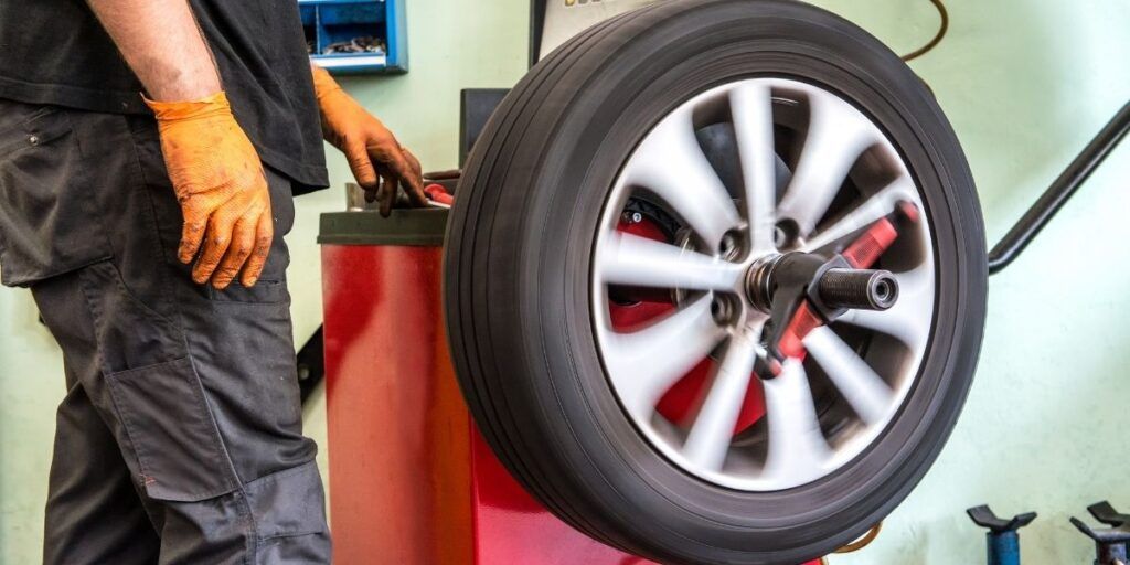 A man is balancing a tire on a machine in a garage. | Country Tire