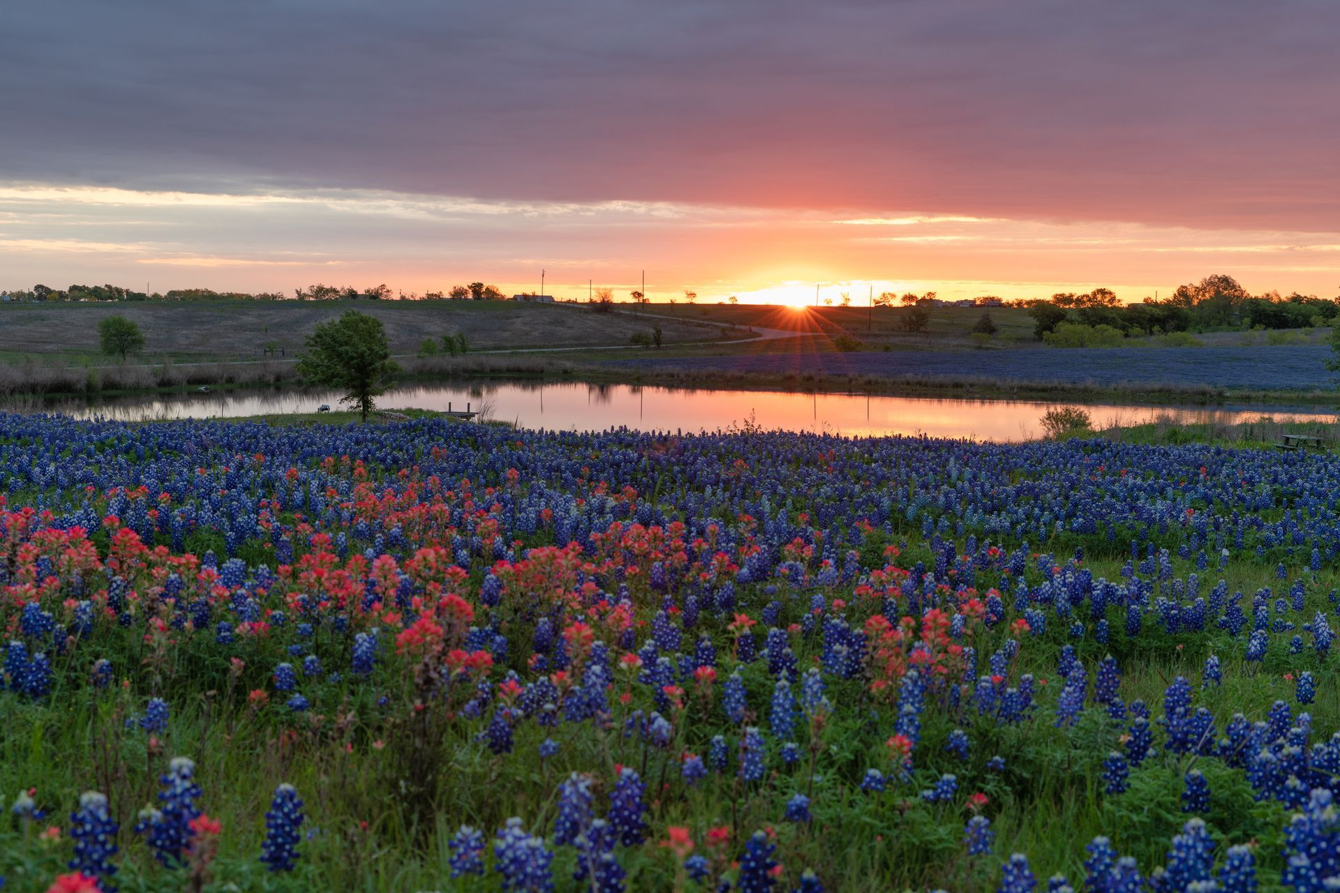 A wooden walkway leading to a gazebo overlooking a body of water at sunset.