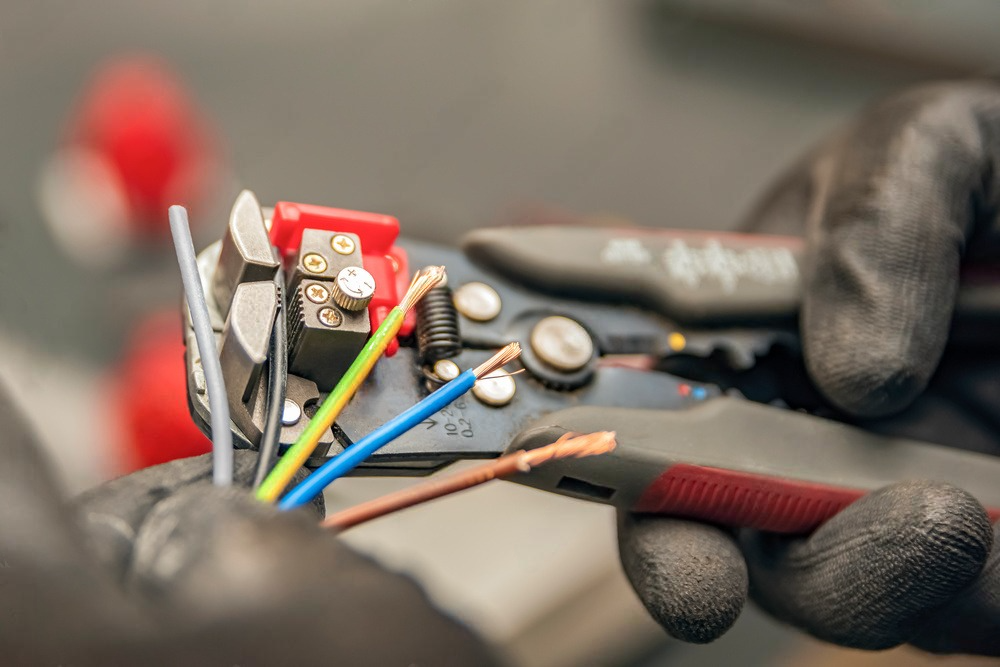 a person is using a wire stripper with a red handle