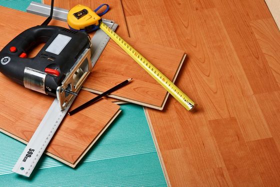 A tape measure a ruler and a jigsaw are on a wooden floor