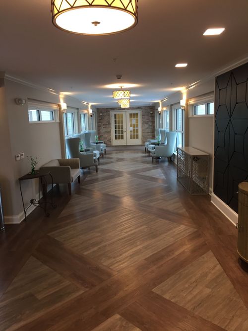 Elegant hallway with herringbone wood floor, pendant lights, and chairs along the walls