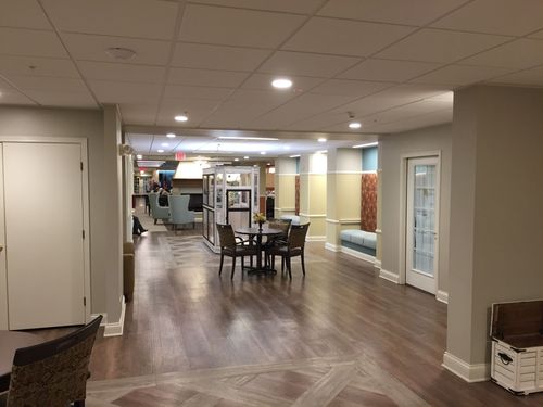 Quiet lobby with wood floors, tables, chairs, and a hallway in a modern building