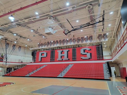 High school gym with red bleachers and large PHS letters on the wall
