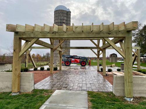 Pergola over a wet stone walkway with a red tractor in a landscaped park