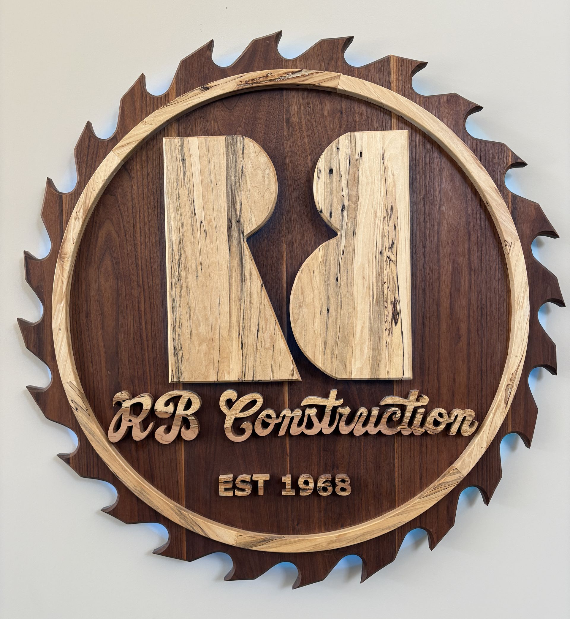 Wooden RB Construction sign with saw blade edges, dark center, and “EST 1958” text