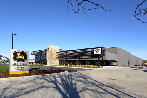 John Deere dealership with a modern showroom and large brand signs on a sunny day