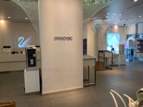 Spacious hotel lobby with reception desk, large white column, and decorative lights overhead