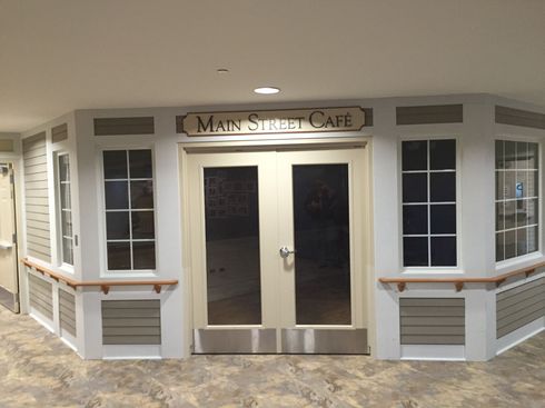 Main Street Cafe entrance with double glass doors and white siding, viewed from outside