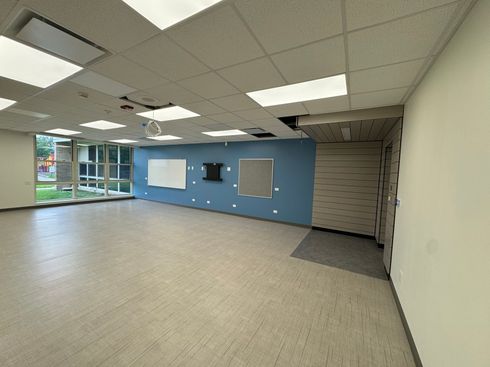 Empty office room with blue accent wall, carpeted floor, and ceiling lights