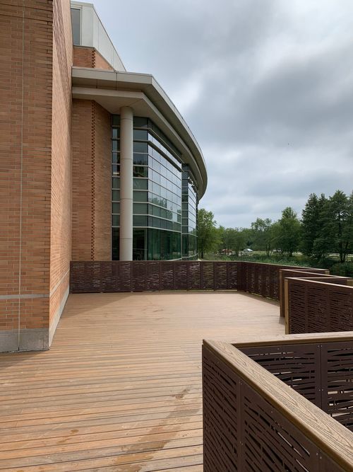 Curved brick building exterior with a glass facade and a brick walkway under cloudy skies