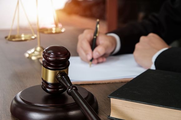 A judge is writing on a piece of paper next to a gavel.