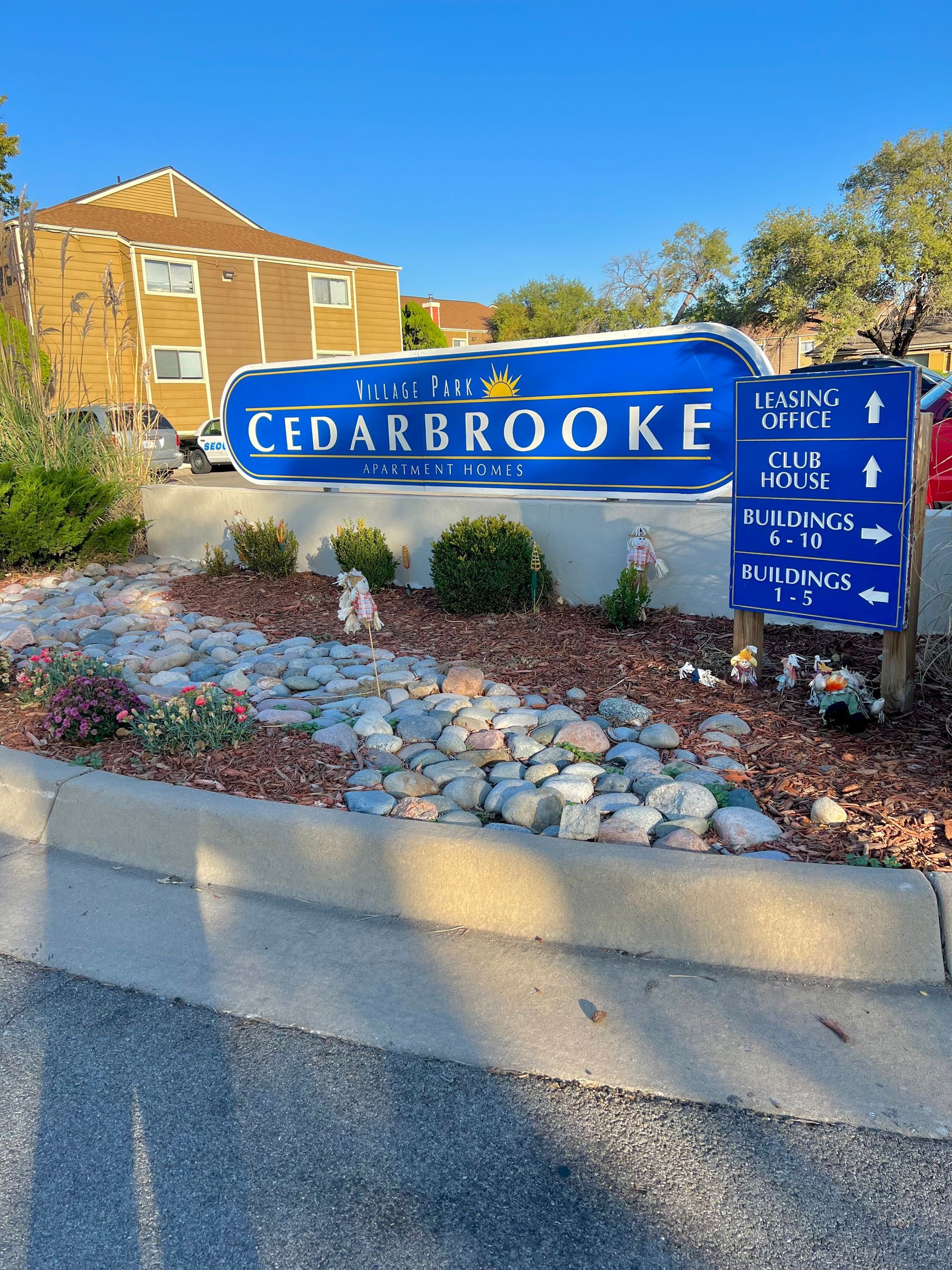 Sign for Cedarbrooke Condominiums with directional arrows against a blue sky.
