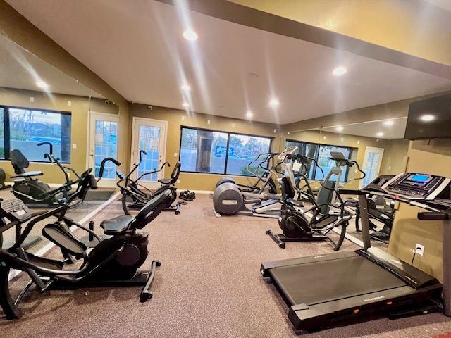 Gym interior with exercise machines, including elliptical trainers, treadmills, and recumbent bikes.
