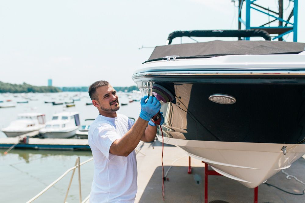 A Man is Polishing the Side of a Boat in a Marina — Furniture & Auto Pride in Kempsey, NSW