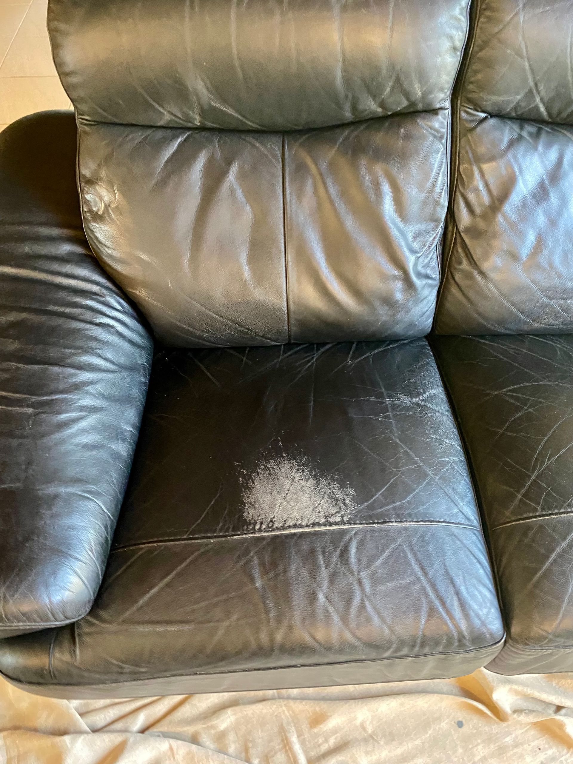 A black leather couch with a stain on the arm rest. — Furniture & Auto Pride In Port Macquarie, NSW