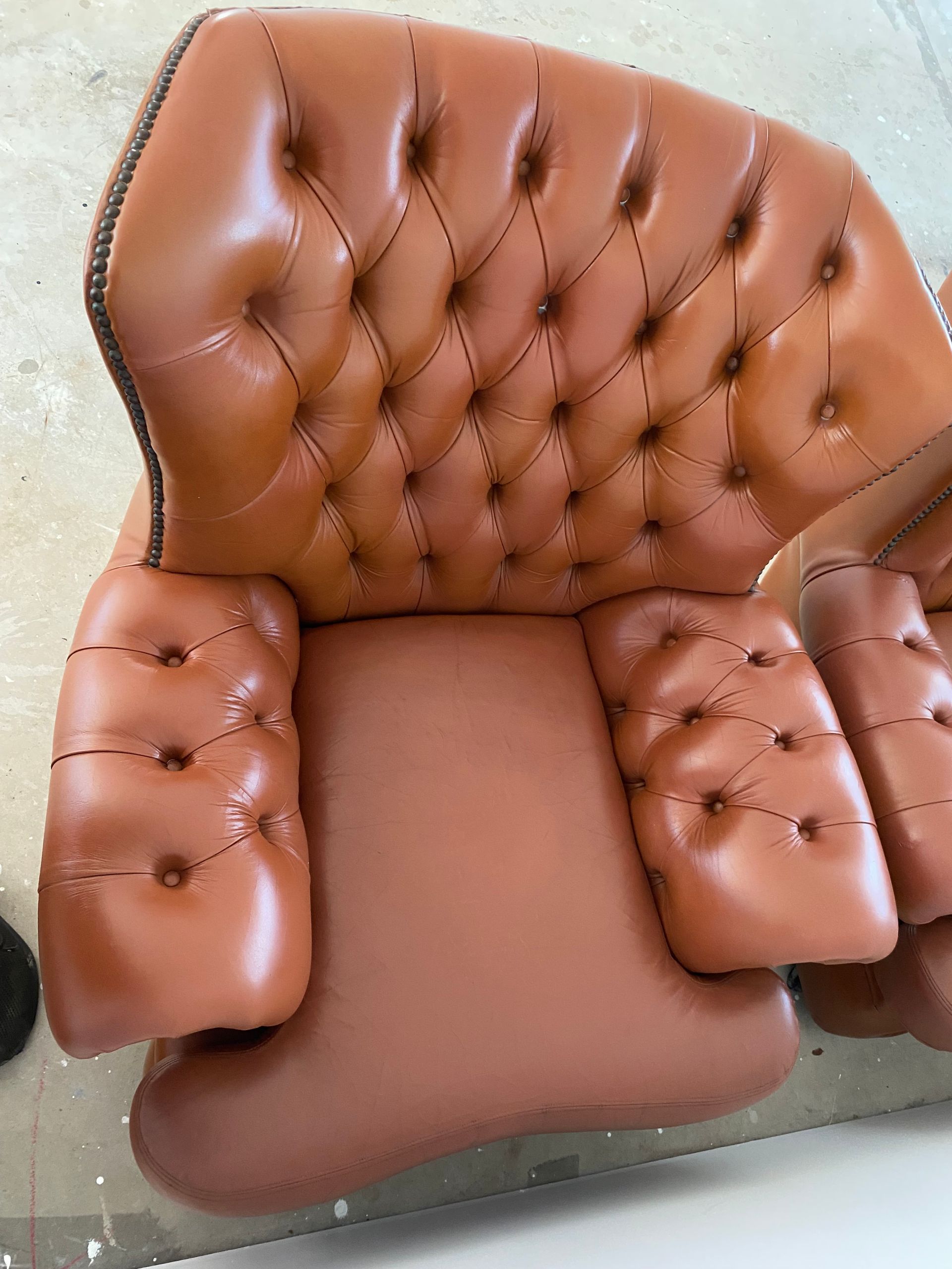 A brown leather chair is sitting on a concrete floor — Furniture & Auto Pride In Port Macquarie, NSW