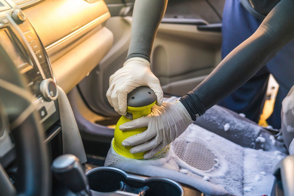 A Person is Cleaning the Interior of a Car With a Machine — Furniture & Auto Pride in Laurieton, NSW
