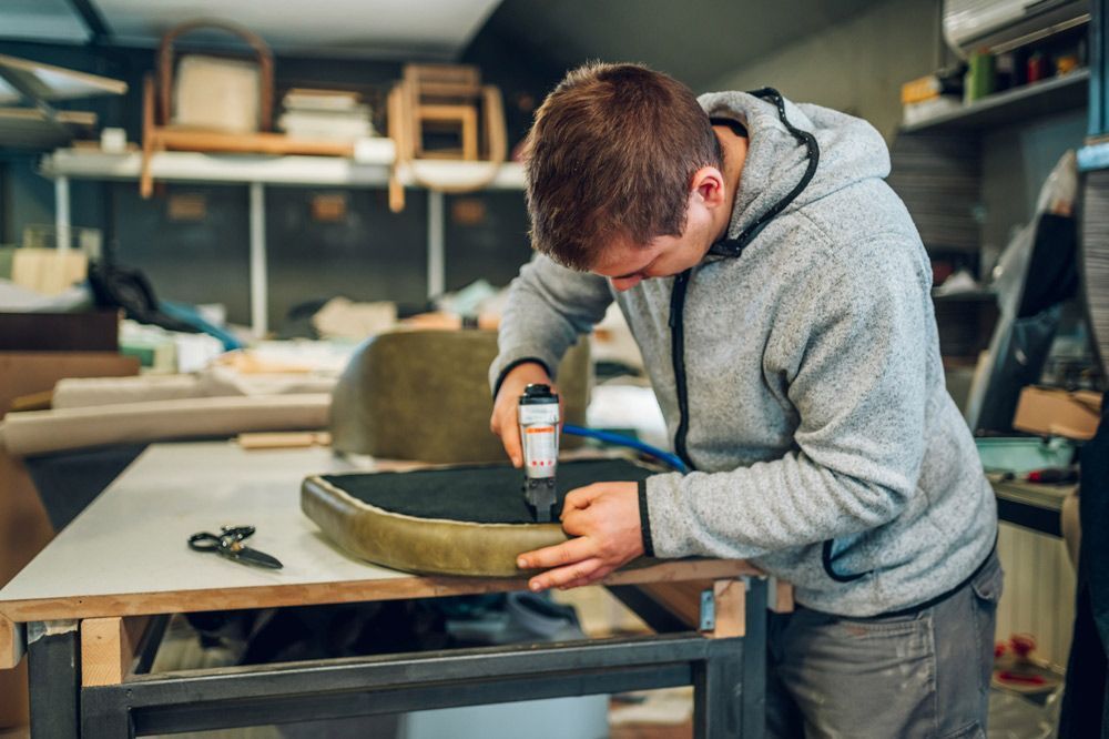 A Man is Working on a Chair in a Workshop — Furniture & Auto Pride in Lake Cathie, NSW