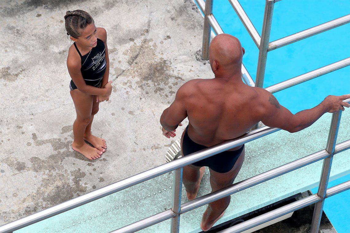 A man and a girl are standing on a diving board talking to each other