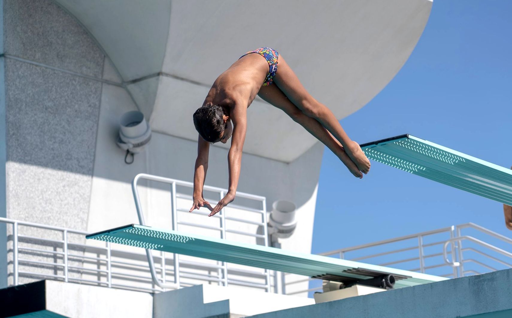 A man is diving off a diving board into a pool