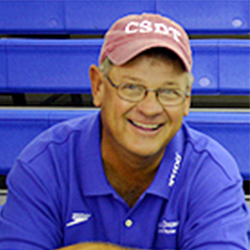 A man wearing a blue shirt and a red hat is smiling.