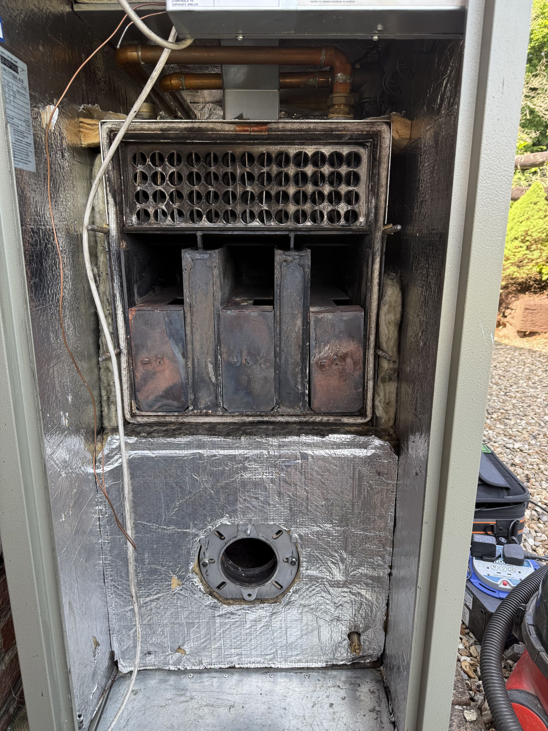 OFTEC engineer servicing an outdoor oil boiler in Hook