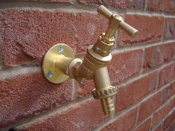 Outdoor tap being installed by a plumber on a brick wall