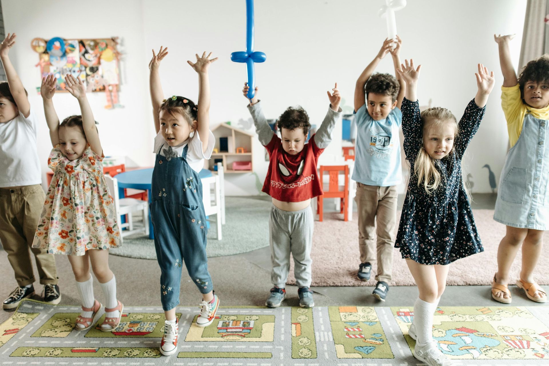 Children in a classroom raising their arms in the air.
