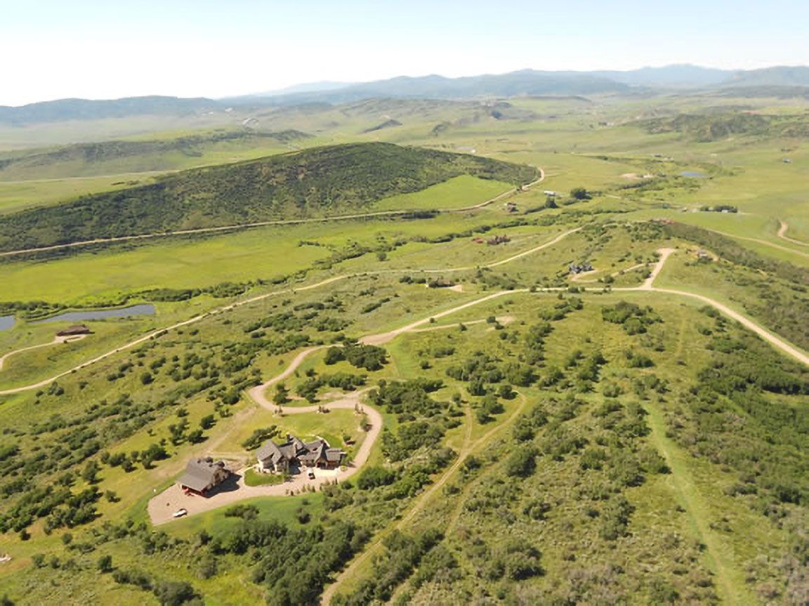 An aerial view of a house in the middle of a lush green field.