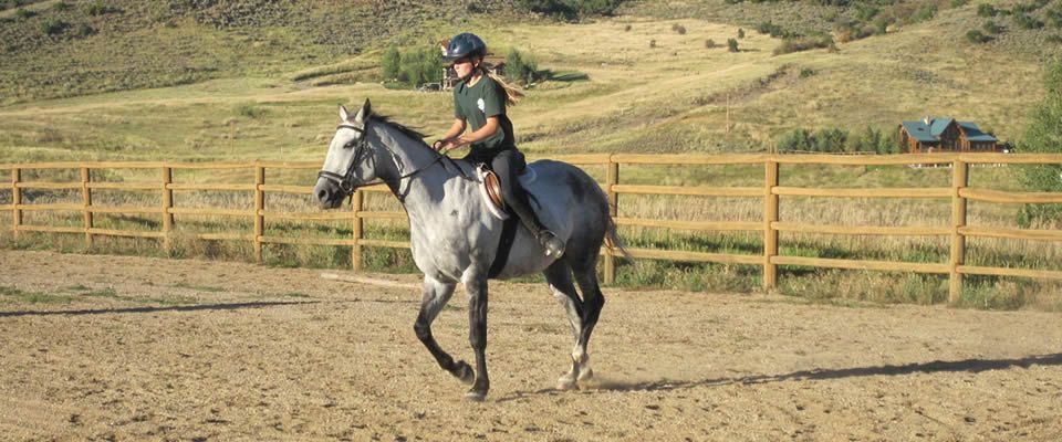 A woman is riding a horse in a dirt field.