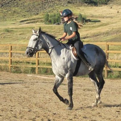 A woman is riding a horse in a dirt field
