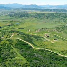 An aerial view of a lush green valley with mountains in the background.