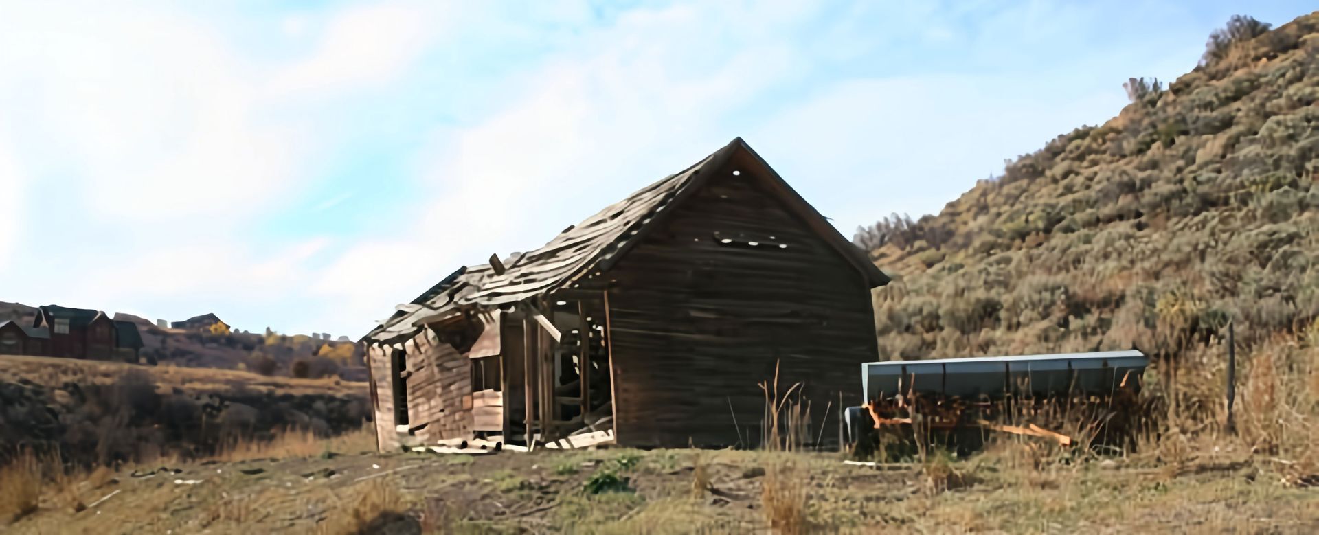 An old wooden house sits in the middle of a field