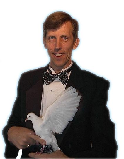 A man in a tuxedo is holding a white dove