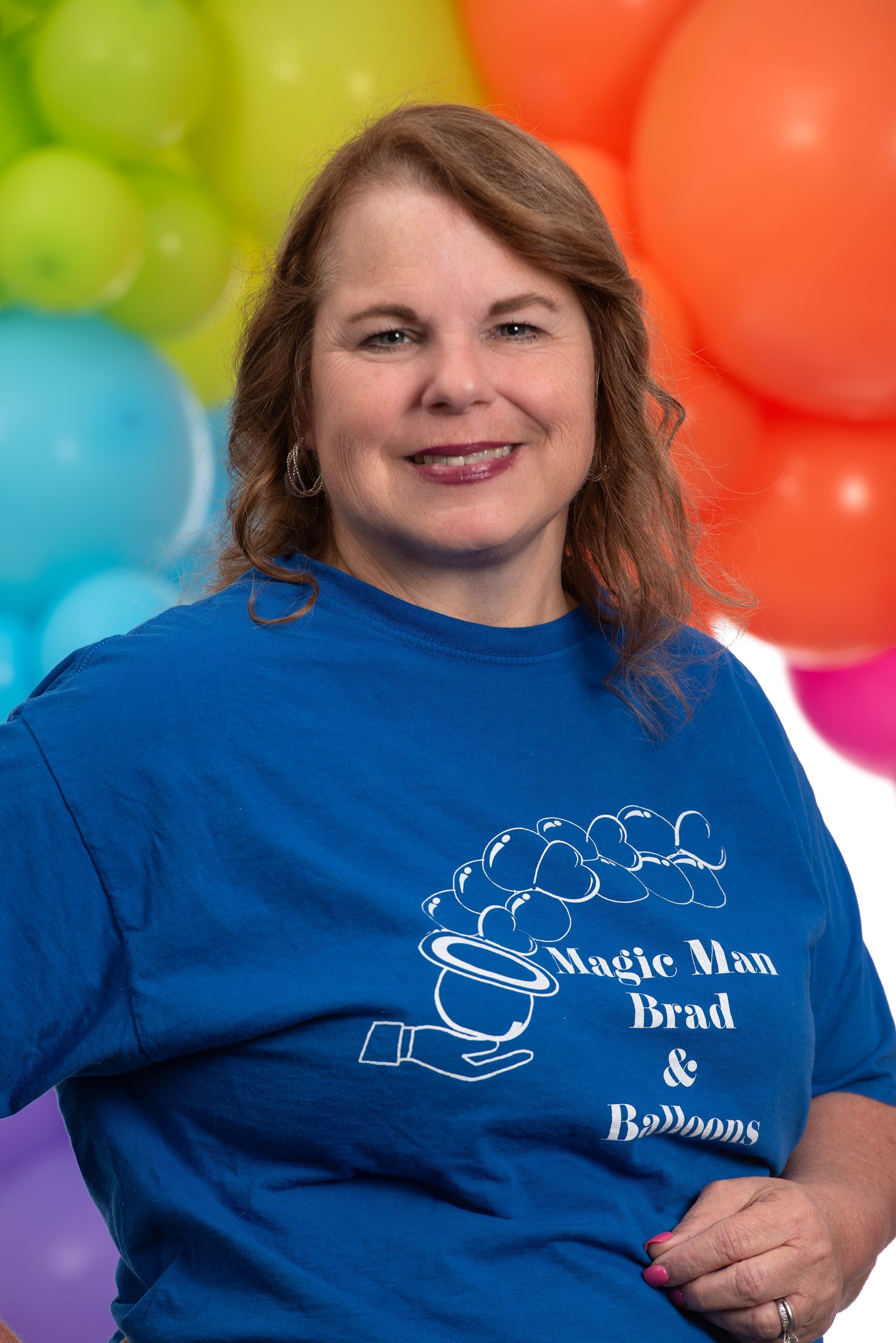 A woman in a blue shirt is standing in front of balloons.