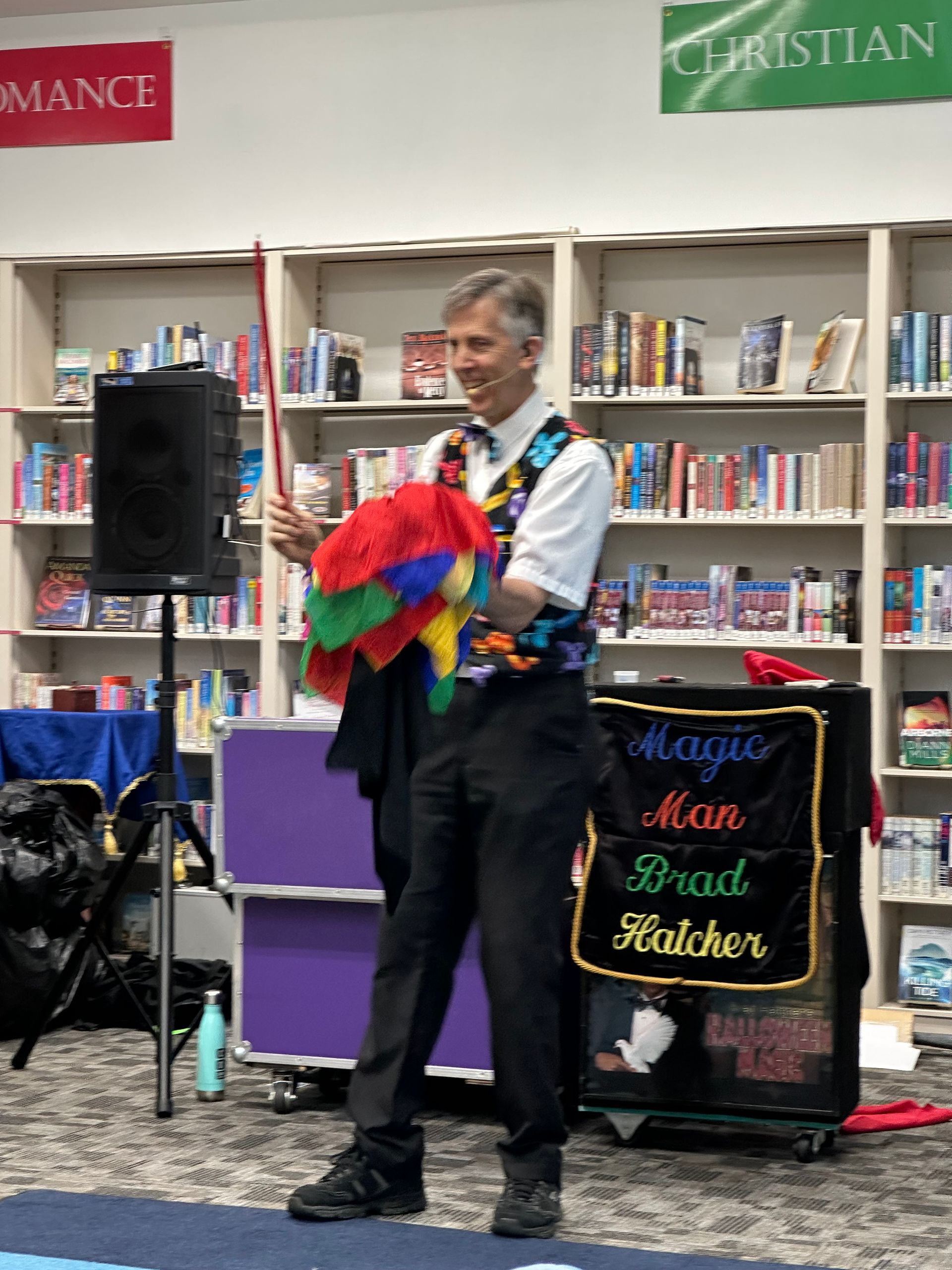 A man is making a balloon animal in a library.
