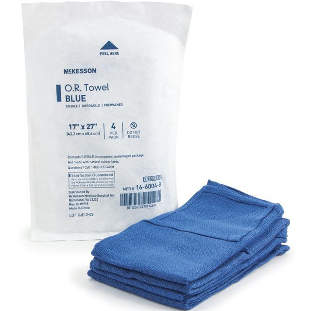 A package of McKesson O.R. blue sterile towels, with a stack of towels in front of the package.