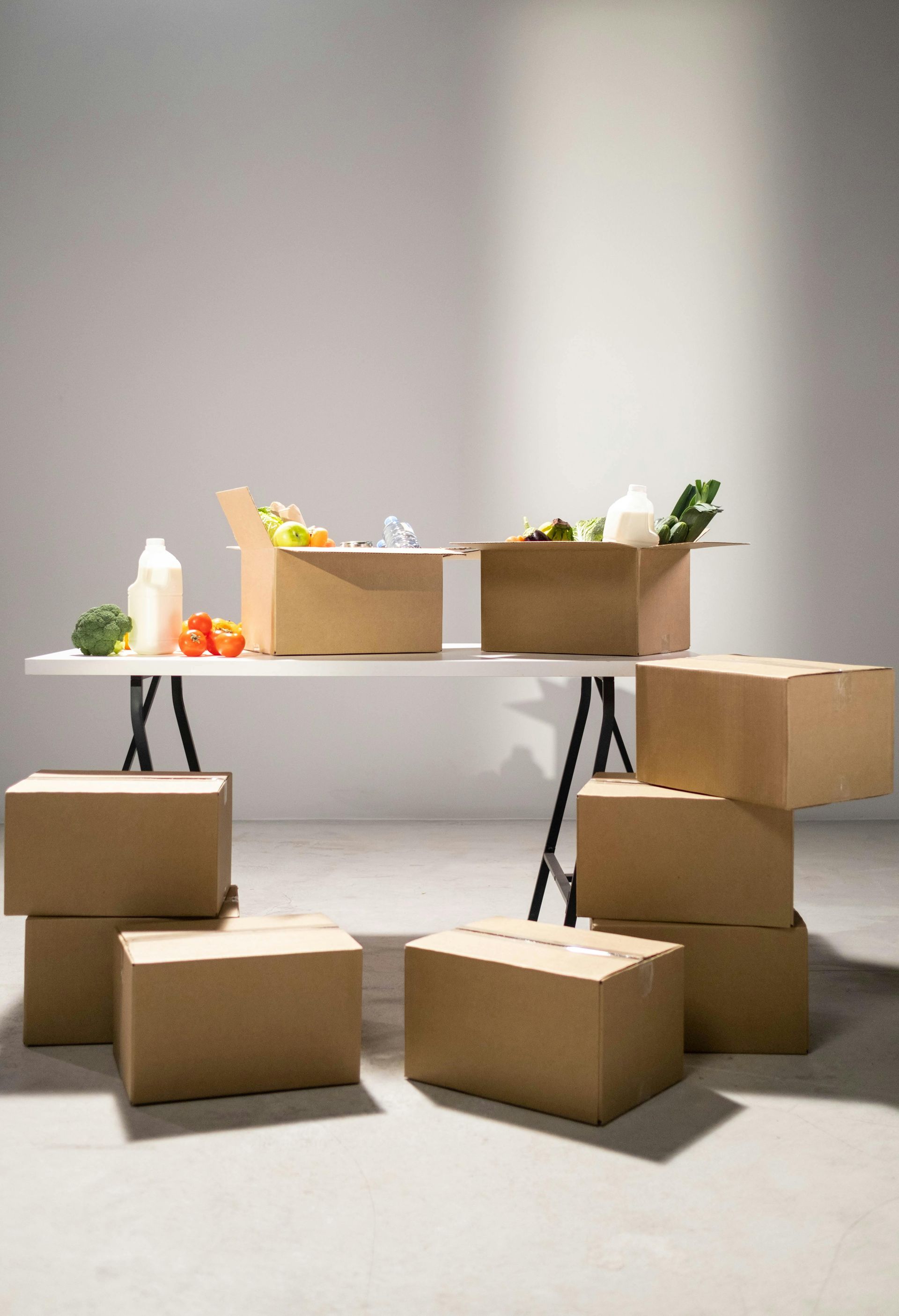 Boxes and groceries on a table and floor, in a room.