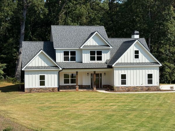 Two-story house with gray siding, stone accents, and a two-car garage, sunny day.